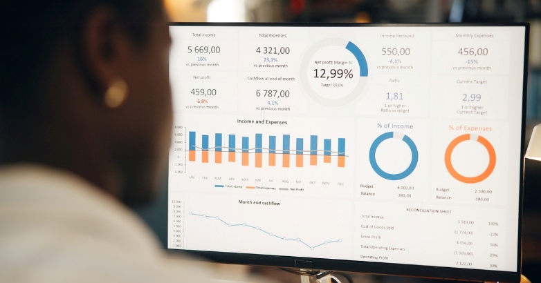 A woman observes a monitor with financial data focused on hotel marketing key performance indicators.