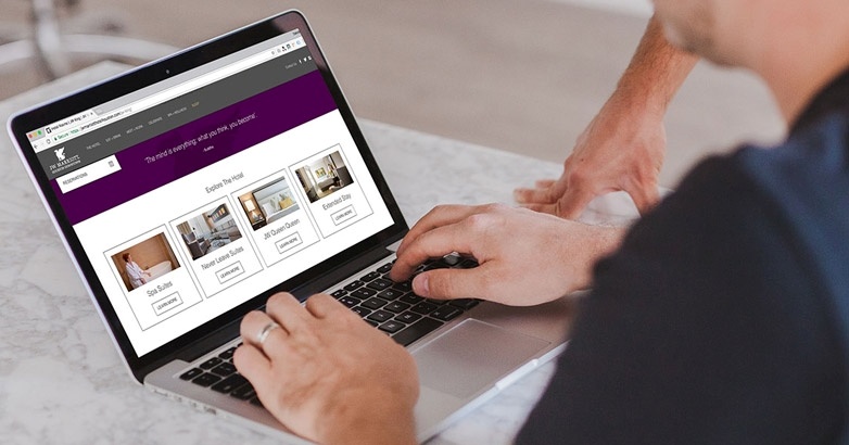 A man engaged with a laptop showing a purple webpage about selecting a hotel marketing agency with proven results.